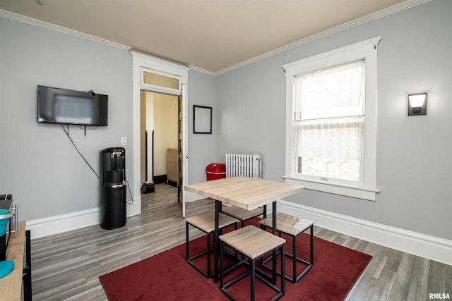 dining space featuring wood finished floors, plenty of natural light, radiator heating unit, baseboards, and crown molding