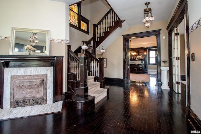 entrance foyer with stairs, hardwood / wood-style floors, a chandelier, and a fireplace