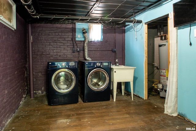 washroom featuring gas water heater, laundry area, brick wall, and independent washer and dryer