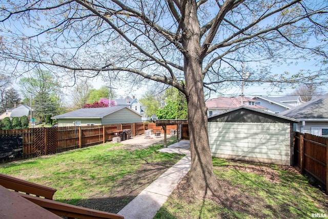view of yard with an outbuilding, a shed, a fenced backyard, and a patio area