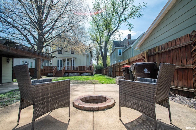 view of patio featuring a fire pit, a deck, and a fenced backyard