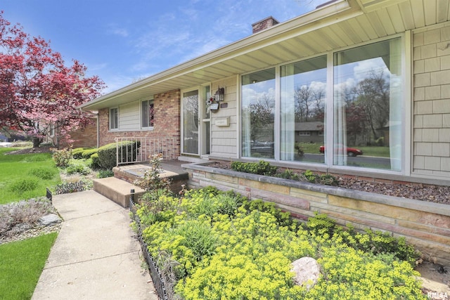 exterior space featuring a chimney and brick siding