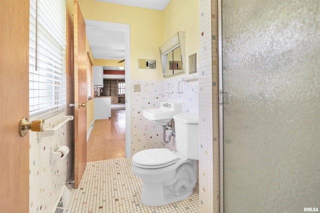 full bath with tile walls, ceiling fan, toilet, and plenty of natural light
