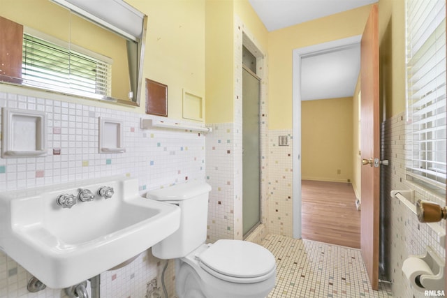 full bath featuring a shower stall, a sink, toilet, tile walls, and tile patterned floors