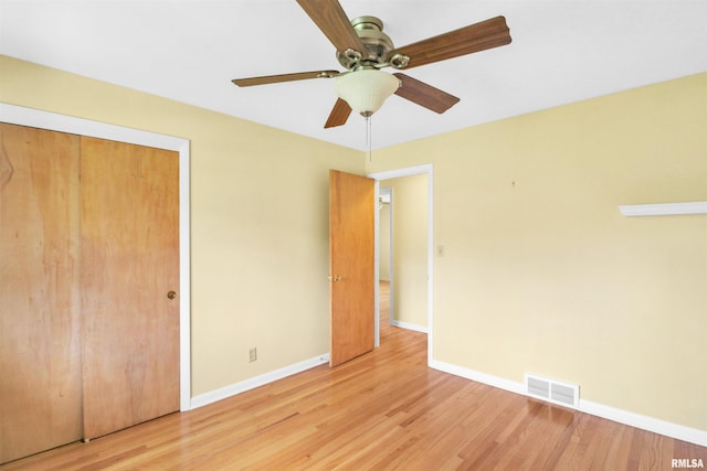 unfurnished bedroom featuring wood finished floors, a closet, ceiling fan, baseboards, and visible vents