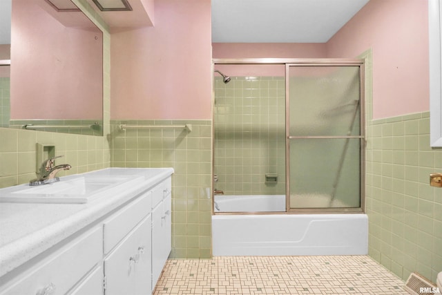 full bathroom with bath / shower combo with glass door, tile patterned floors, a wainscoted wall, and tile walls