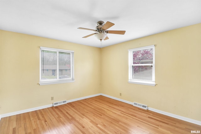 unfurnished room featuring baseboards, visible vents, a ceiling fan, and light wood finished floors