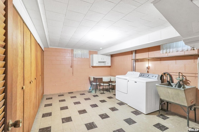 laundry area with a sink, separate washer and dryer, laundry area, and concrete block wall