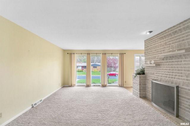 unfurnished living room with visible vents, baseboards, light colored carpet, and a fireplace