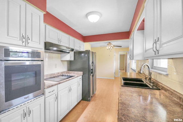 kitchen featuring black appliances, a sink, backsplash, and under cabinet range hood