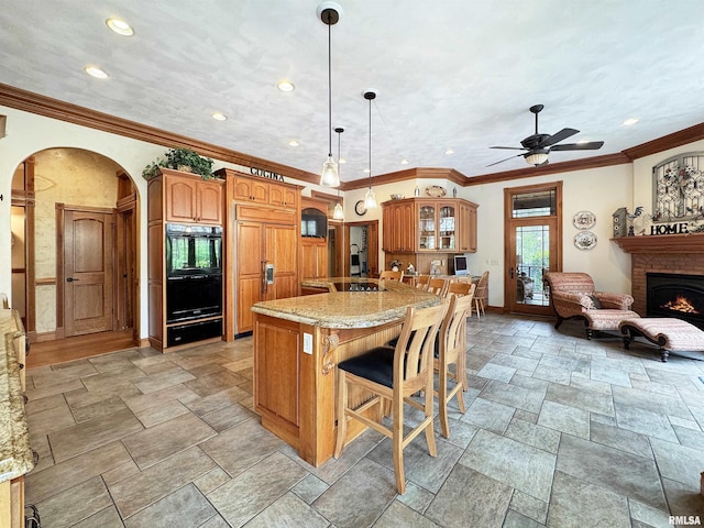 kitchen with dobule oven black, stone tile floors, brown cabinets, arched walkways, and a warming drawer