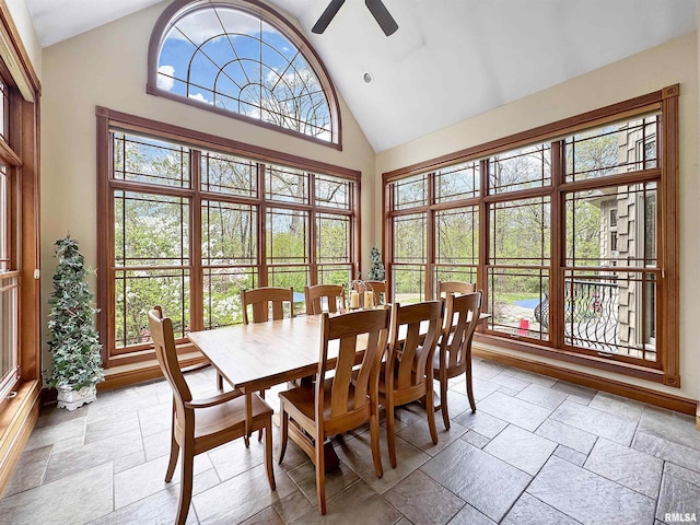 dining room featuring high vaulted ceiling, ceiling fan, and stone tile floors