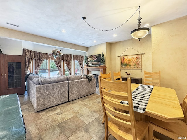 living area with stone finish flooring, visible vents, and recessed lighting
