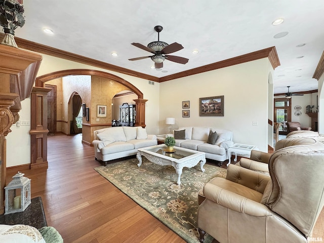 living room with a ceiling fan, arched walkways, decorative columns, and ornamental molding