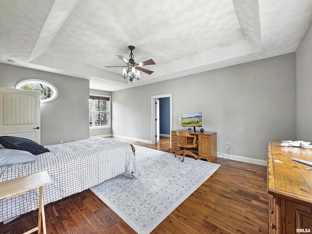 bedroom featuring baseboards, a tray ceiling, and dark wood-style floors