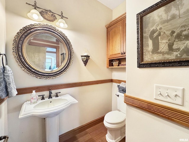 half bath featuring toilet, baseboards, and wood finished floors