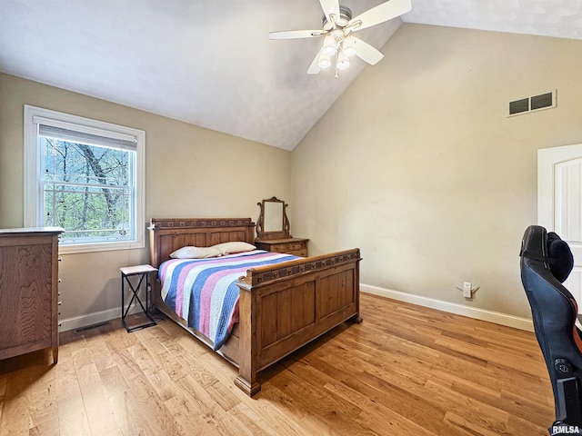 bedroom featuring visible vents, baseboards, ceiling fan, light wood-style flooring, and vaulted ceiling