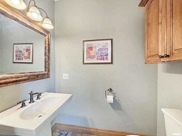 bathroom featuring toilet, baseboards, and a sink