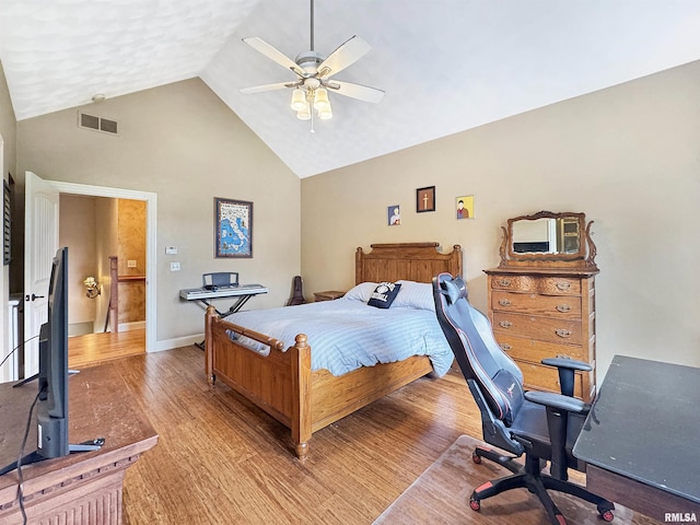 bedroom with ceiling fan, visible vents, wood finished floors, high vaulted ceiling, and baseboards