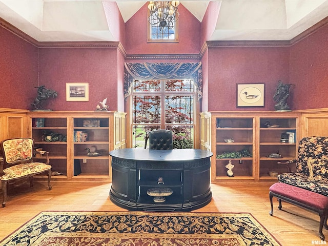 office space featuring a high ceiling, a chandelier, wainscoting, and light wood-type flooring