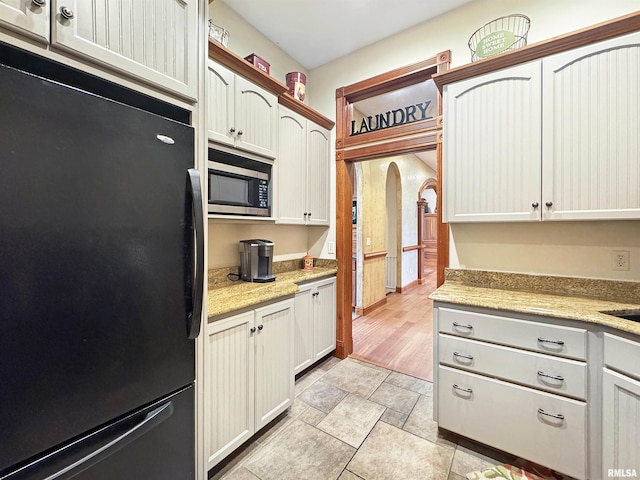 kitchen featuring freestanding refrigerator, arched walkways, and stainless steel microwave