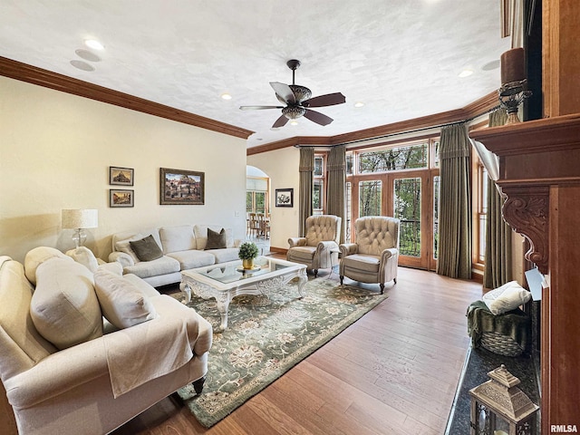 living area featuring crown molding, arched walkways, ceiling fan, and hardwood / wood-style flooring
