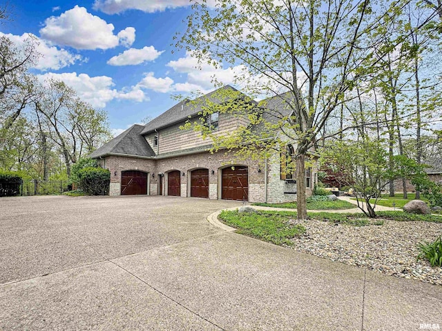 view of home's exterior with a shingled roof, fence, driveway, and stone siding