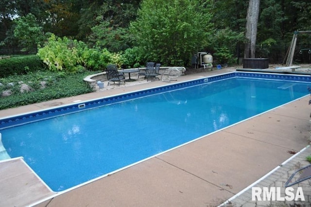 outdoor pool with a diving board and a patio area
