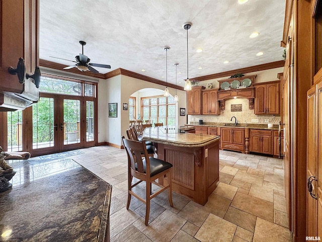 kitchen with brown cabinets, stone tile floors, french doors, and a center island