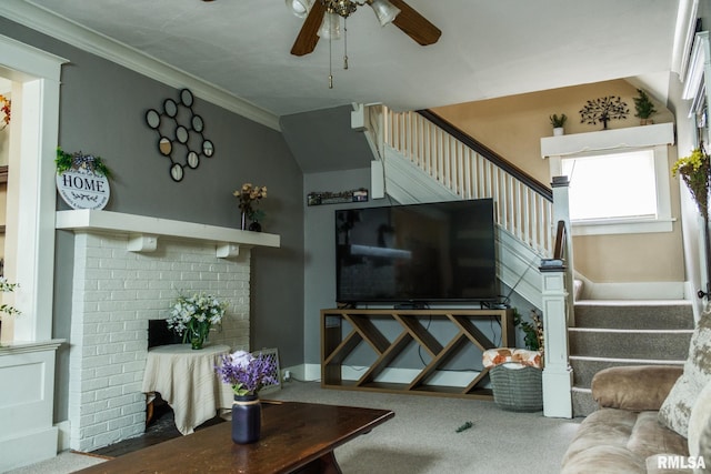 living area featuring carpet, ceiling fan, a fireplace, stairway, and crown molding