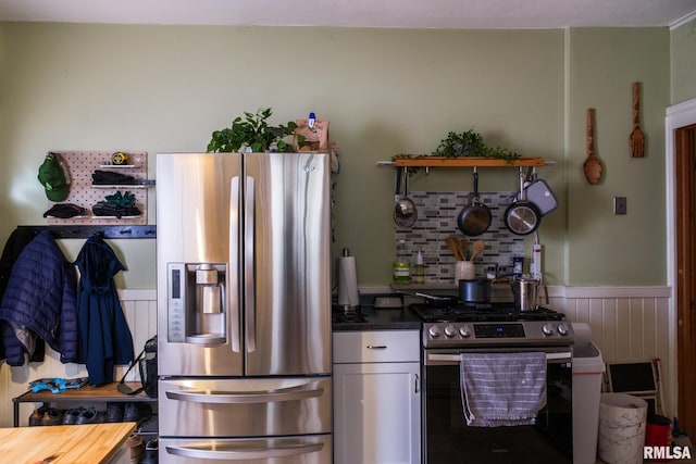 kitchen featuring white cabinetry, stainless steel appliances, and a wainscoted wall