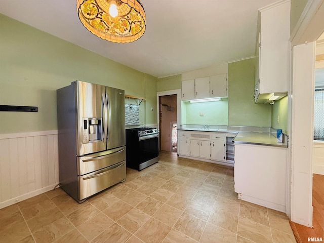 kitchen with white cabinetry, a wainscoted wall, appliances with stainless steel finishes, and light countertops
