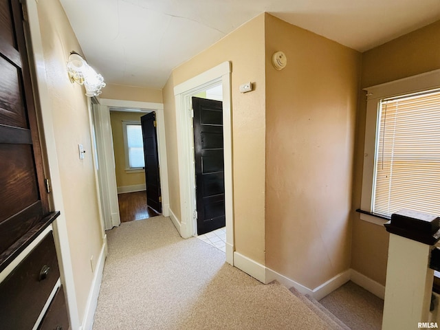 hallway featuring baseboards and light colored carpet