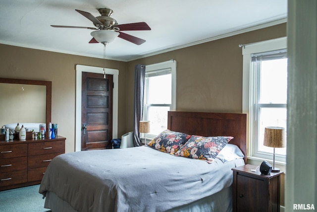 carpeted bedroom with crown molding and a ceiling fan