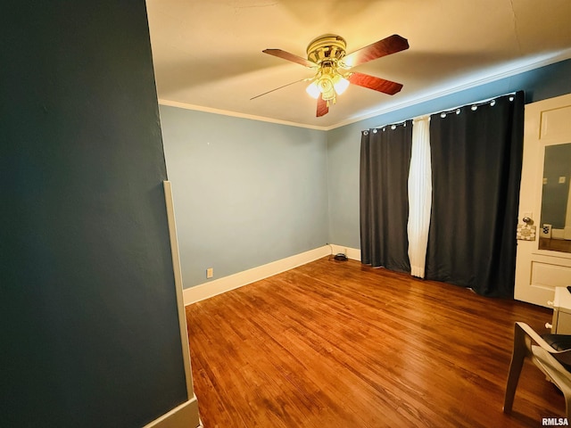unfurnished room with ornamental molding, ceiling fan, wood finished floors, and baseboards