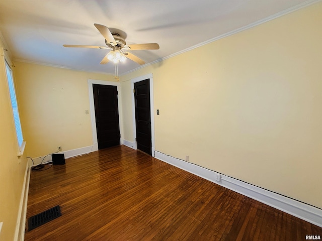 spare room featuring ceiling fan, visible vents, baseboards, ornamental molding, and wood finished floors