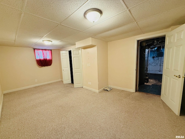 finished below grade area featuring baseboards, carpet floors, and a paneled ceiling