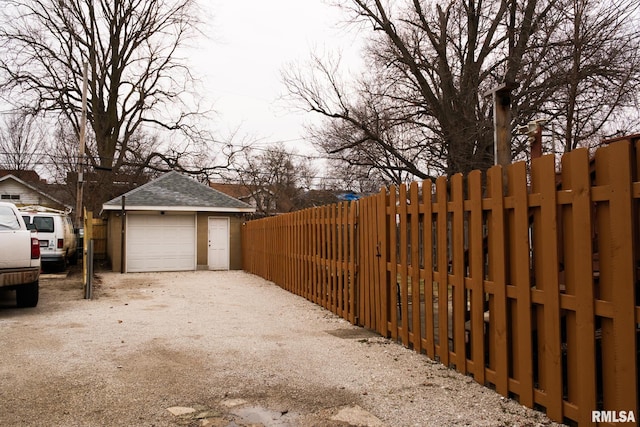 detached garage featuring fence and driveway