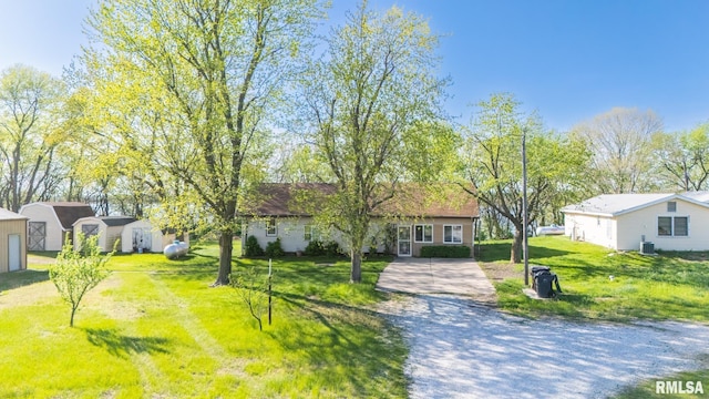 ranch-style home with an outbuilding, a storage shed, central AC unit, driveway, and a front lawn
