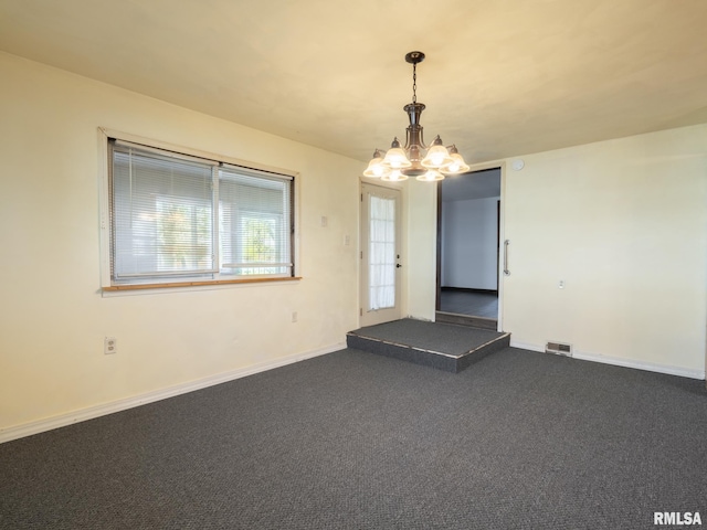 unfurnished room with baseboards, dark colored carpet, visible vents, and an inviting chandelier