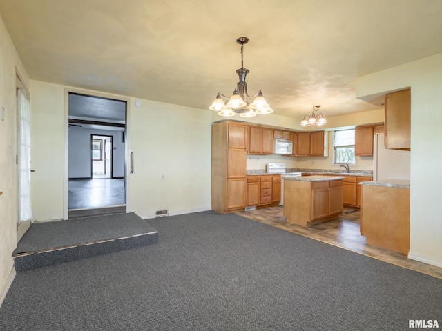 kitchen featuring white appliances, an inviting chandelier, light countertops, a sink, and a center island