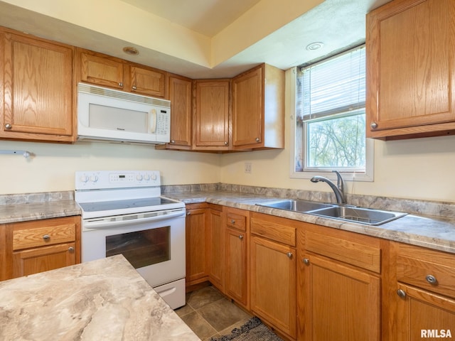 kitchen with white appliances, brown cabinets, light countertops, and a sink