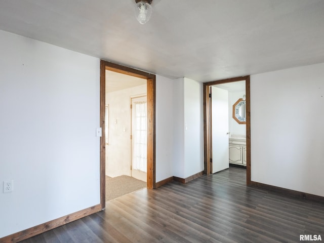 spare room with baseboards and wood finished floors
