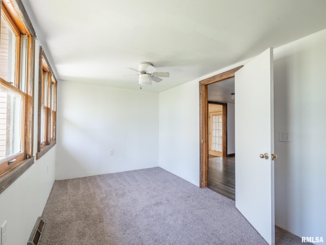 carpeted spare room with ceiling fan and visible vents
