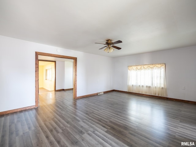 unfurnished room with baseboards, ceiling fan, and dark wood-style floors