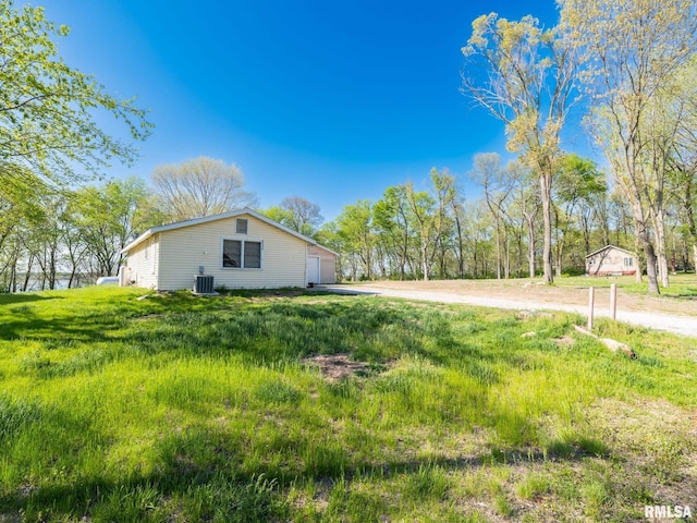 view of side of home featuring dirt driveway and central AC unit