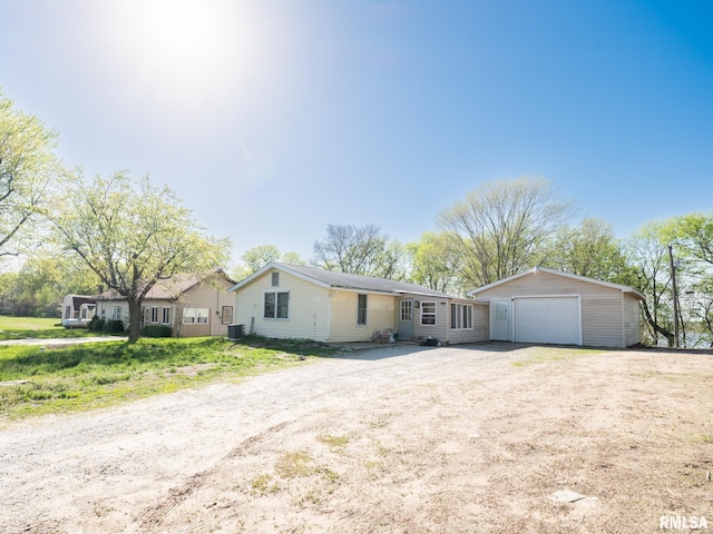ranch-style home featuring a detached garage, driveway, and central AC