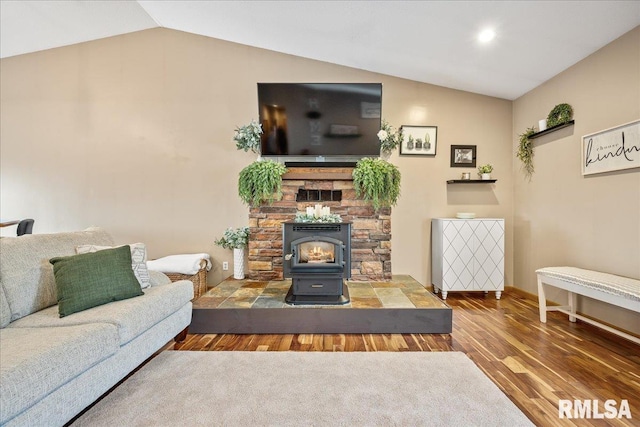 living room featuring baseboards, a wood stove, wood finished floors, and lofted ceiling