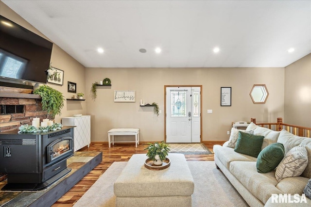 living area with a wood stove, recessed lighting, wood finished floors, and baseboards