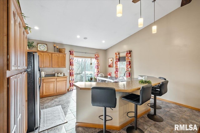 kitchen with light brown cabinets, light countertops, a kitchen bar, vaulted ceiling, and a kitchen island with sink